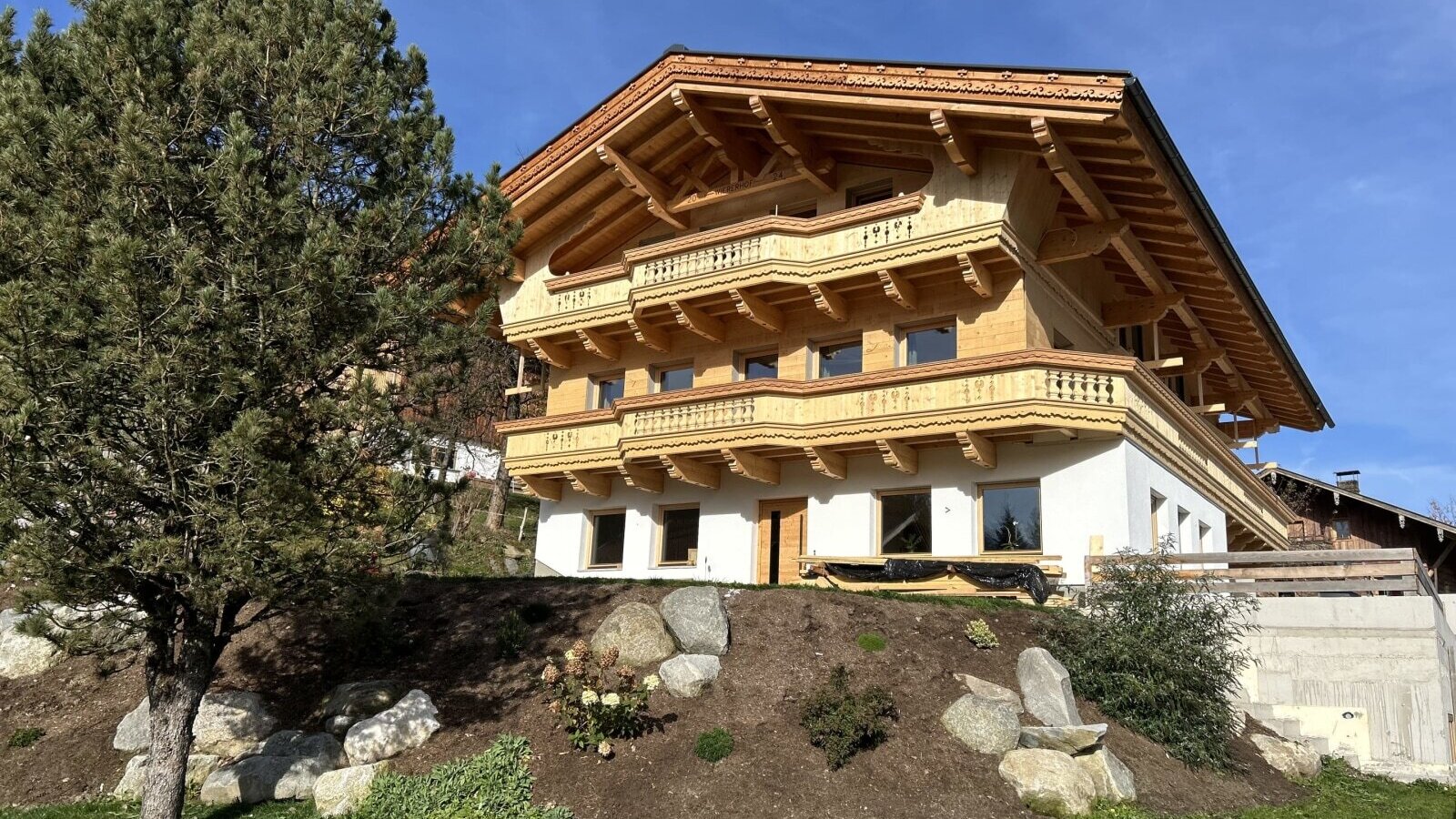 Außenansicht des Bauernhofs mit traditionellen Holzbalkonen und einer Fassade aus Holz und Weißputz.