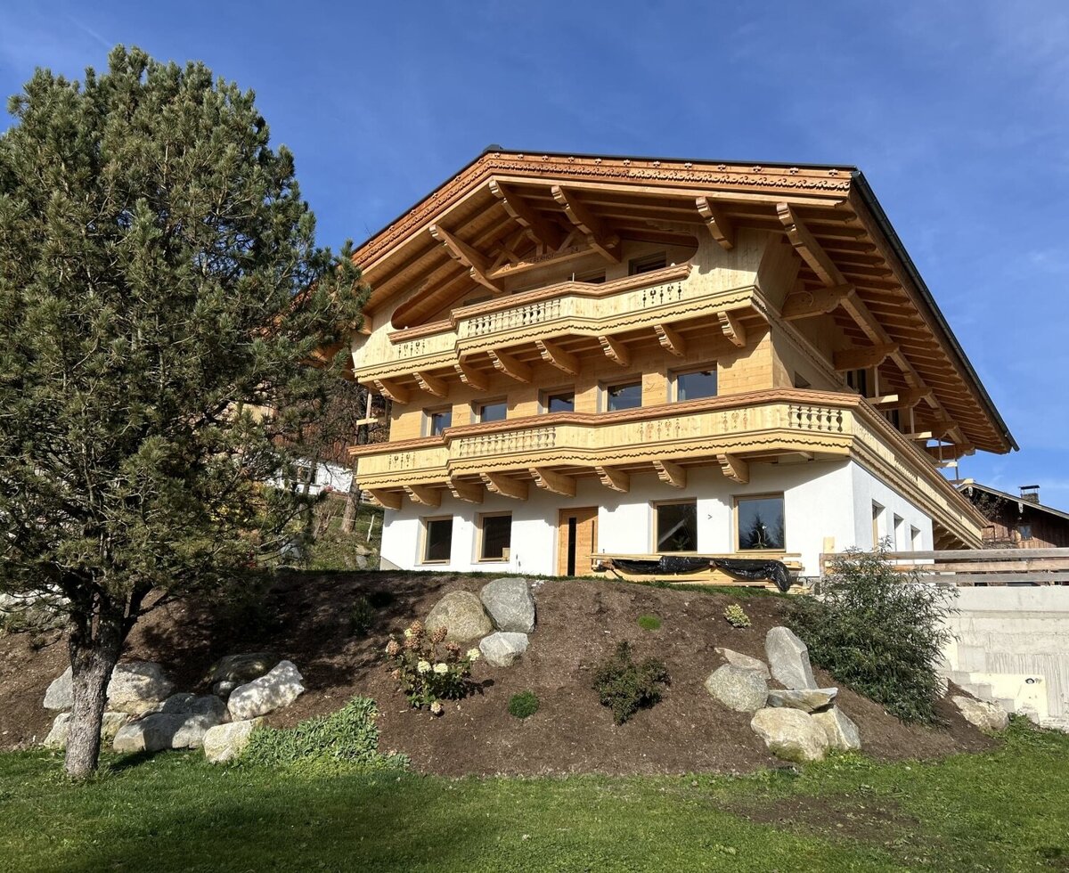 Außenansicht des Bauernhofs mit traditionellen Holzbalkonen und einer Fassade aus Holz und Weißputz.