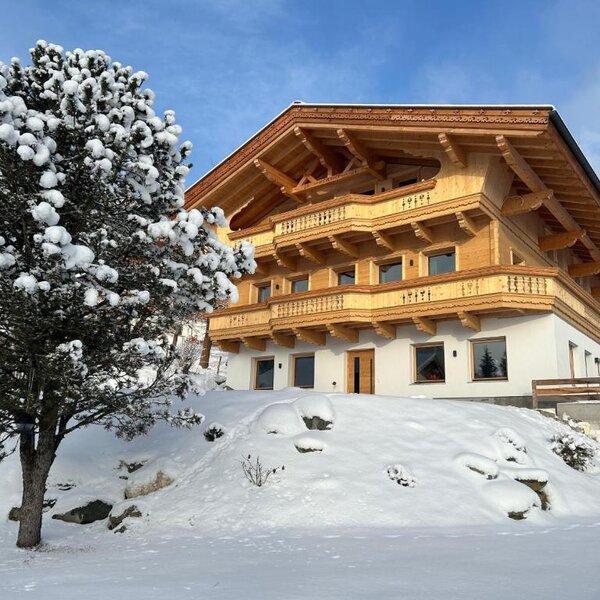 Außenansicht des Bauernhofs im Winter, mit Holzfassade, Balkonen und schneebedeckter Umgebung.