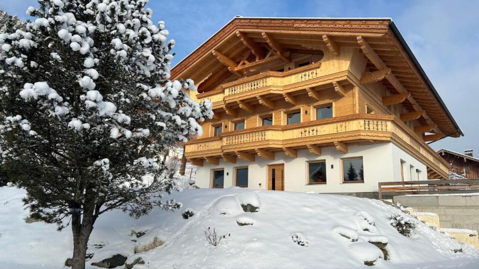 Außenansicht des Bauernhofs im Winter, mit Holzfassade, Balkonen und schneebedeckter Umgebung.