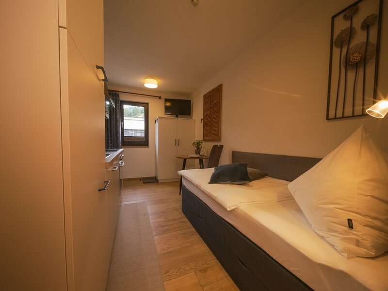 Einzelzimmer im Bauernhof mit integrierter Küchenzeile, Esstisch, Kleiderschrank und Fernseher.