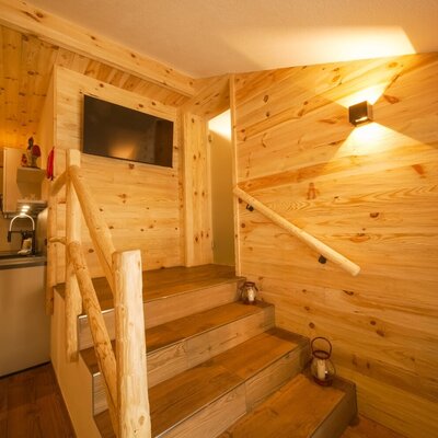 Holztreppe mit Geländer und TV-Bereich im Bauernhof, angrenzend an eine Küchenzeile.