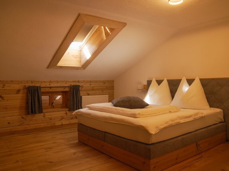 Das Schlafzimmer im Bauernhof verfügt über ein großes Bett, Holzboden, eine Holzvertäfelung und ein Dachfenster.