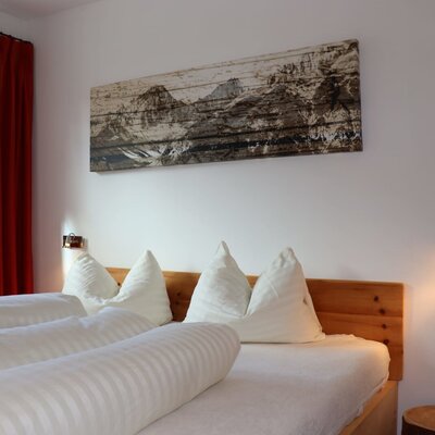 Ein gemütliches Schlafzimmer im Appartement mit einem komfortablen Holzbett, weicher weißer Bettwäsche und stimmungsvoller Beleuchtung.