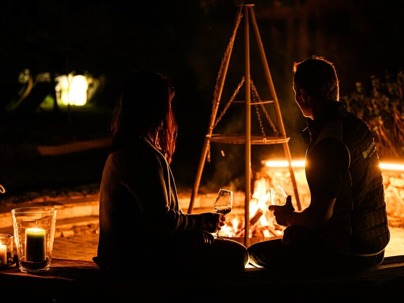 Ein gemütlicher Abend am knisternden Lagerfeuer des Bauernhofs mit einem Glas Wein.