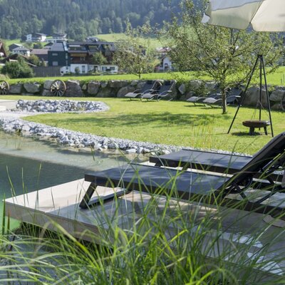 Der Bauernhof bietet einen Naturbadeteich mit Liegestühlen, eine Liegewiese und einen Außenloungebereich sowie Pferde auf der Weide.