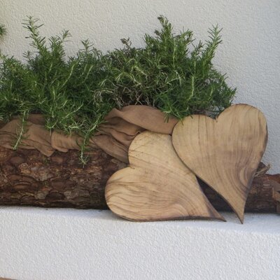 Dekoratives Holzgefäß mit Rosmarin und Holzherzen auf dem Bauernhof.