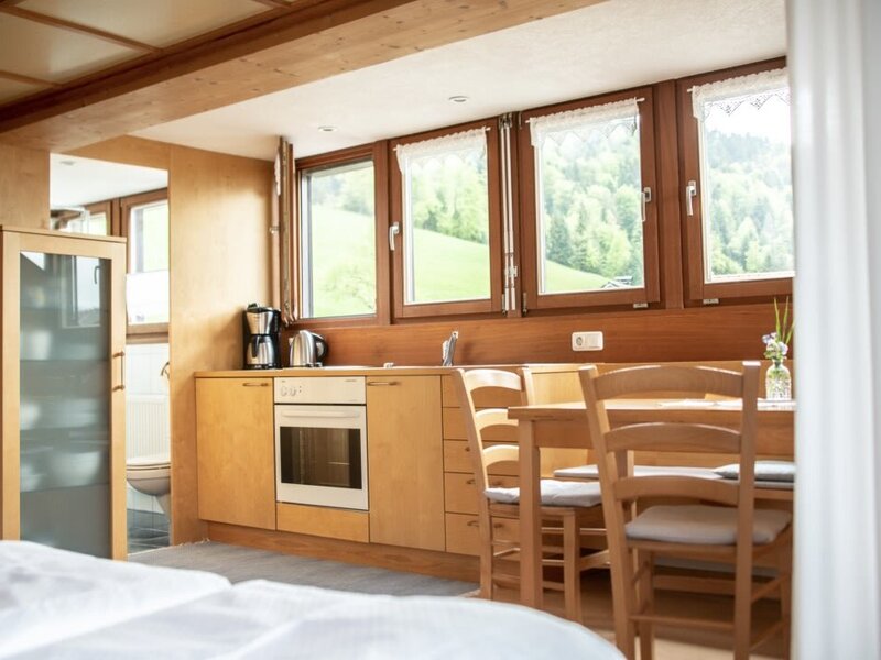 Küchen- und Essbereich in einer Wohnung auf dem Bauernhof, ausgestattet mit Backofen, Esstisch und Fenstern mit Bergblick.