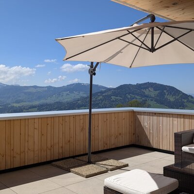 Die sonnige Terrasse des Bauernhofs mit gemütlichen Lounge-Möbeln und einem weitreichenden Blick auf die umliegenden Berge.