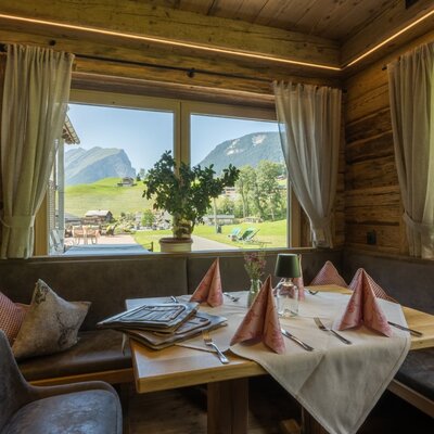 Eine gemütliche Sitzecke im Bauernhof mit Holzvertäfelung und einem herrlichen Blick auf die umliegenden Berge.