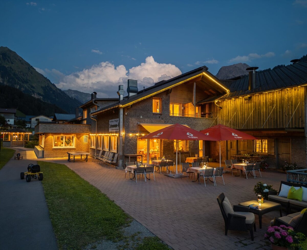 Die einladende Terrasse des Bauernhofs in den Abendstunden mit gemütlichen Sitzbereichen und stimmungsvoller Beleuchtung.