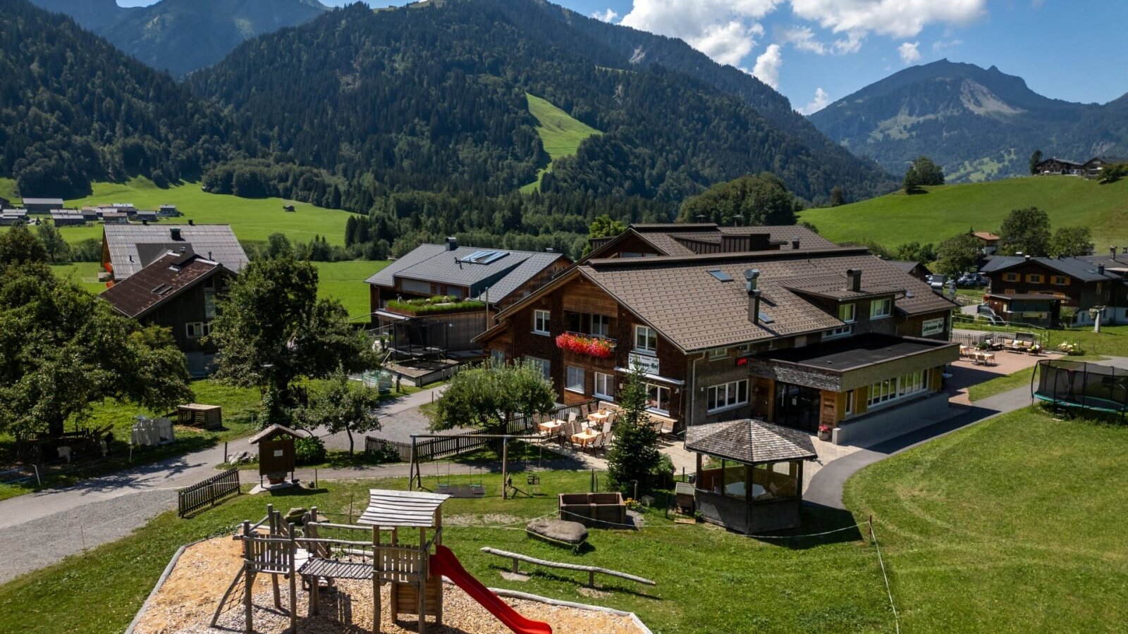 Der einladende Bauernhof mit einem weitläufigen Spielplatz vor der Kulisse der beeindruckenden Allgäuer Alpen.