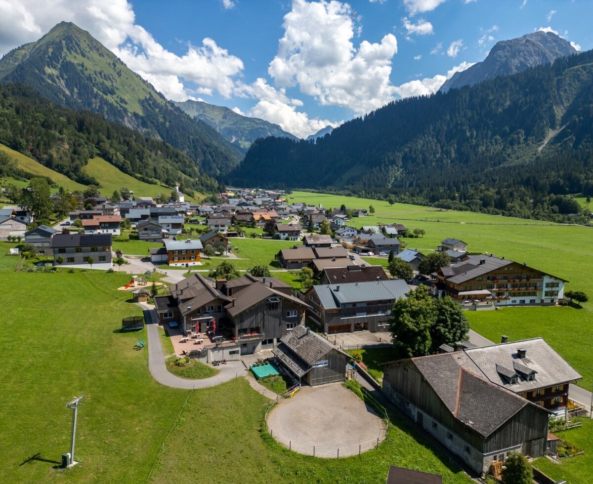 Der einladende Bauernhof, eingebettet in ein idyllisches Tal und umgeben von einer malerischen Bergkulisse.