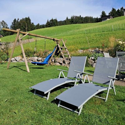 Der Garten des Bauernhofs bietet eine Schaukel, eine Rutsche, Sonnenliegen und eine Terrasse mit Sitzgelegenheiten.