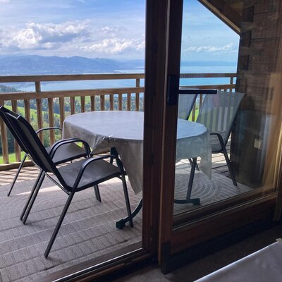 Einladender Balkon des Bauernhofs mit gemütlicher Sitzecke und herrlichem Blick auf den See und die umliegende Hügellandschaft.