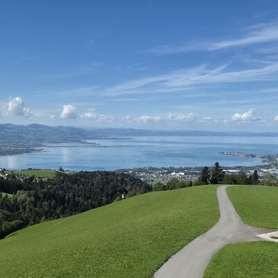 Weitläufiger Ausblick vom Bauernhof auf den schimmernden See und die umliegenden grünen Hügel.
