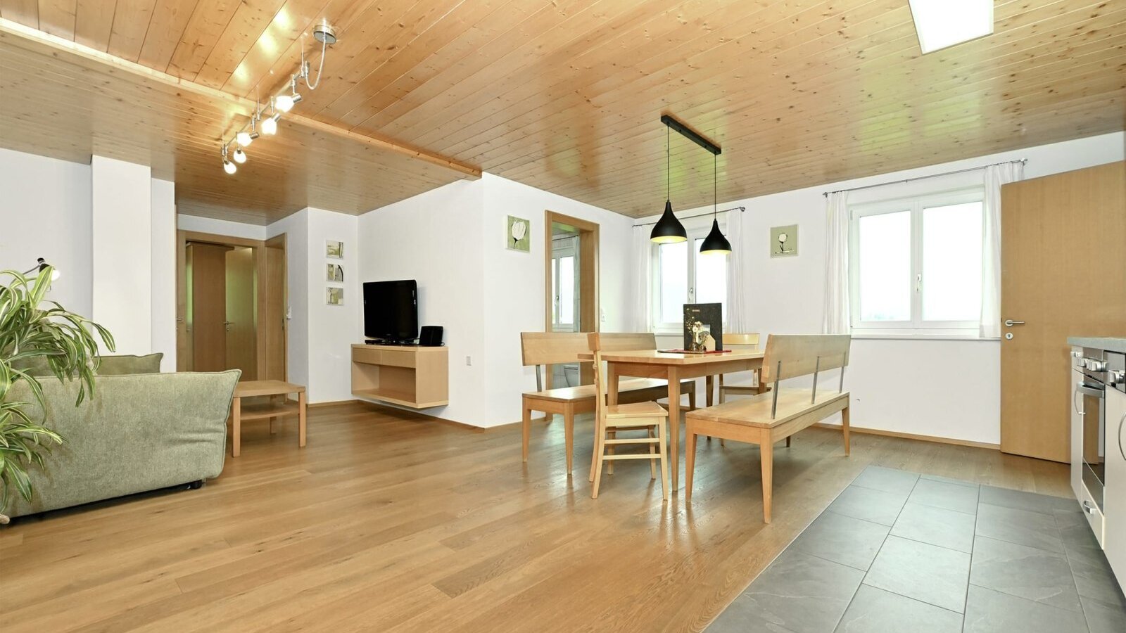 Der offene Wohnbereich der Ferienwohnung mit Sofa, TV, Esstisch und der vollausgestatteten Wohnküche.
