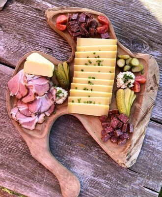 Eine Brotzeitplatte mit Käse, Schinken, Wurst, Butter und Essiggurken, als Mahlzeit in der Ferienwohnung.