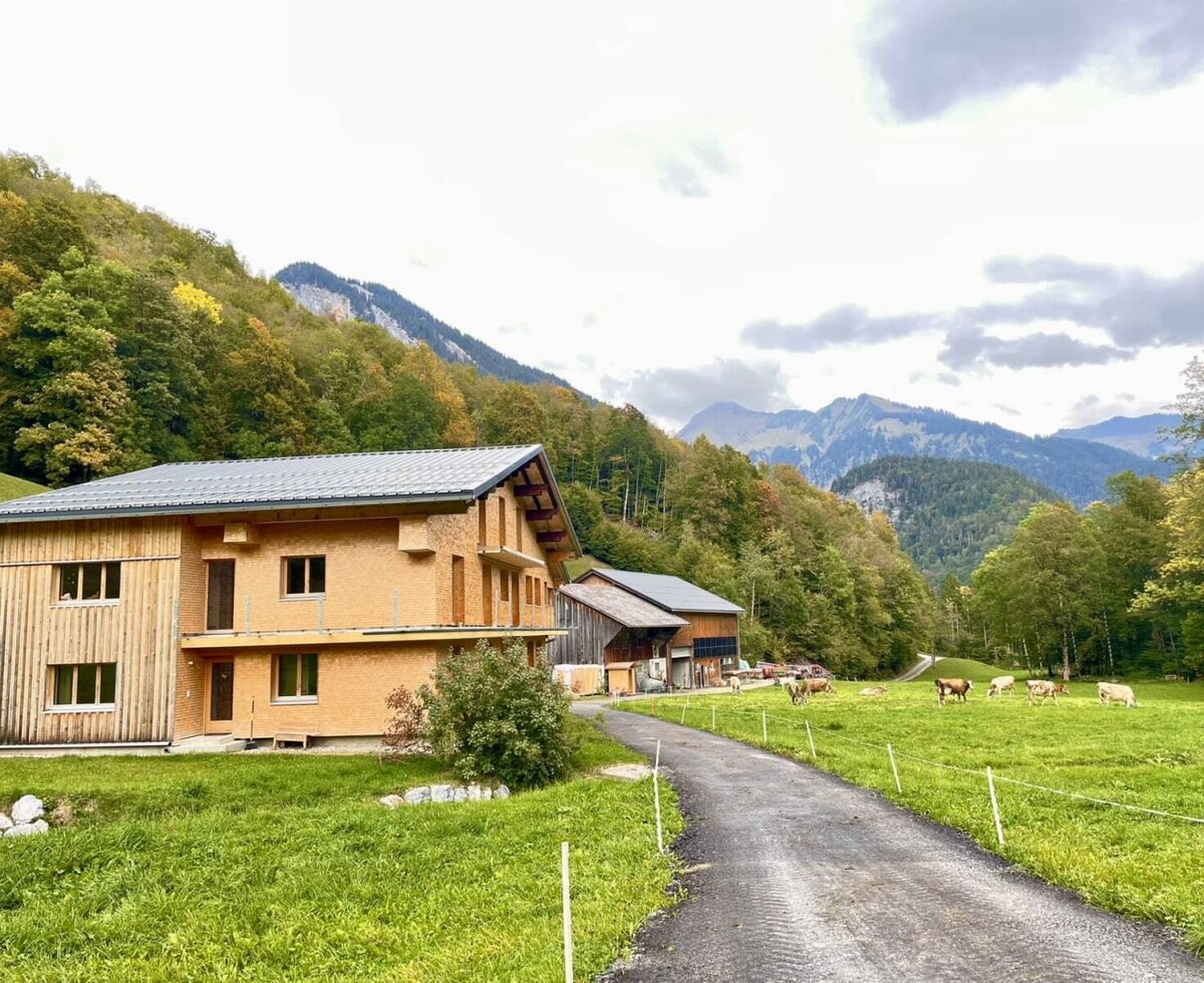 Die einladende Ferienwohnung in einem modernen Holzgebäude, umgeben von grünen Weiden und einer malerischen Bergkulisse.