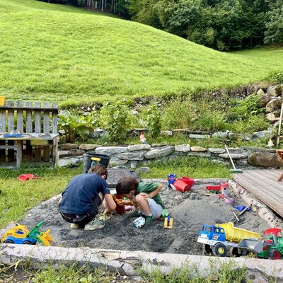 Ein großer, einladender Sandkasten im grünen Garten der Ferienwohnung bietet reichlich Platz zum Spielen.