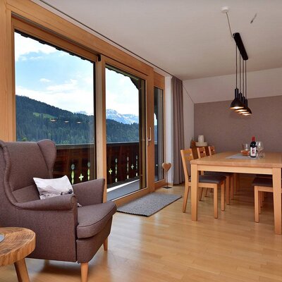 Großzügiger Wohn- und Essbereich der Ferienwohnung mit Bergblick und Zugang zum Balkon.