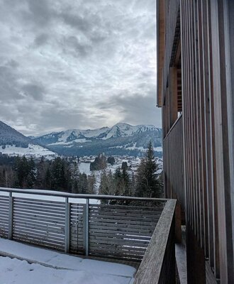 Blick vom Balkon des Bauernhofs auf die verschneite Berglandschaft und das Tal.