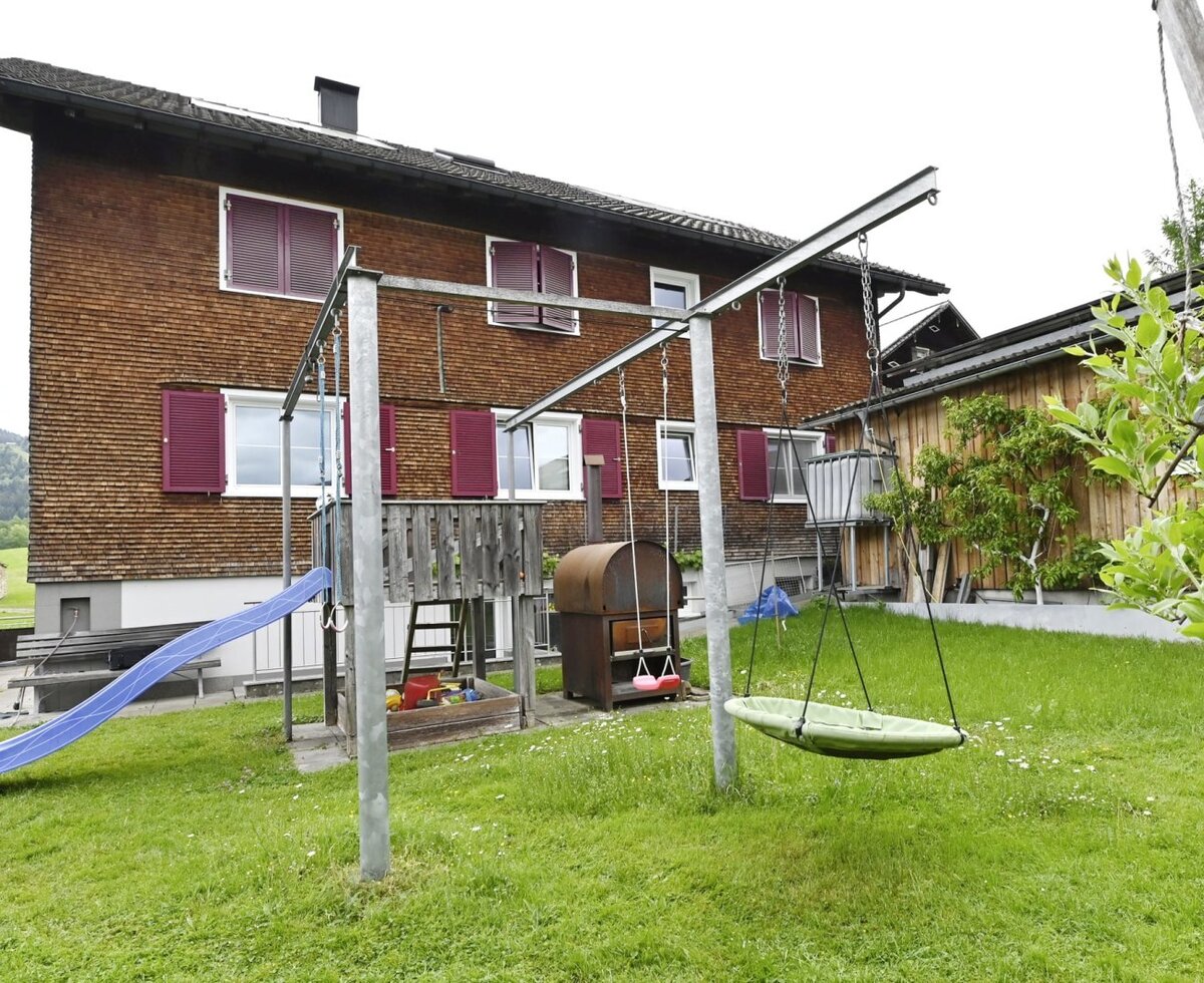 Kinderspielplatz im Garten des Bauernhofs mit Rutsche, Schaukeln und Sandkasten.