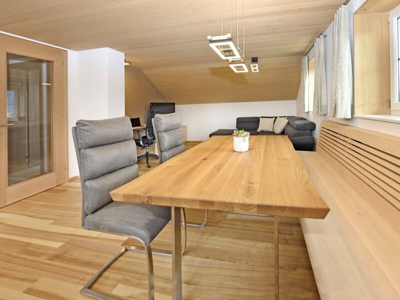 Der Essbereich der Ferienwohnung mit Holztisch, Stühlen und Eckbank, angrenzend an den Wohnbereich mit Sofa.