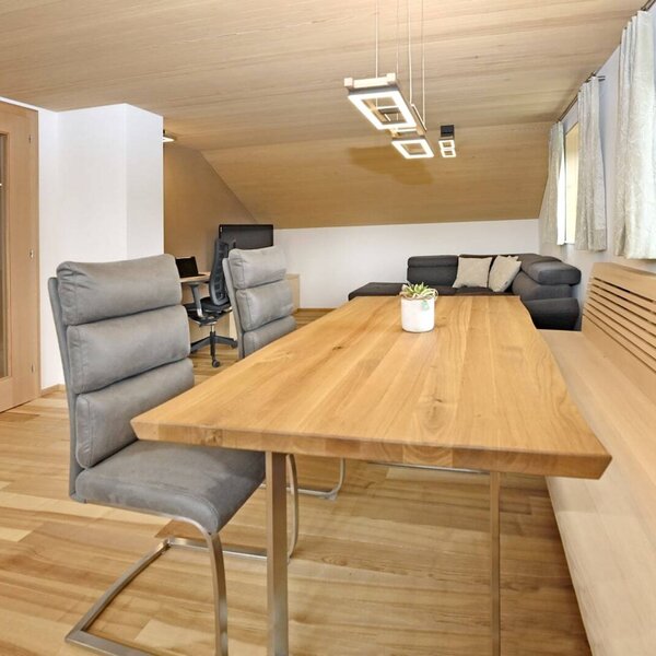 Der Essbereich der Ferienwohnung mit Holztisch, Stühlen und Eckbank, angrenzend an den Wohnbereich mit Sofa.