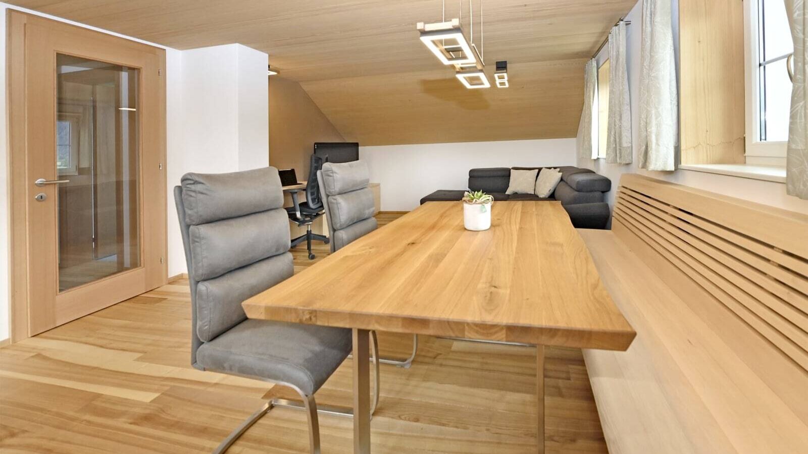 Der Essbereich der Ferienwohnung mit Holztisch, Stühlen und Eckbank, angrenzend an den Wohnbereich mit Sofa.