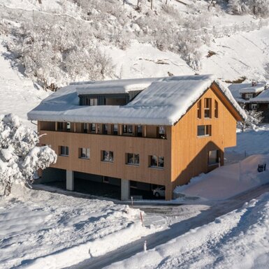 Die neuen Ferienwohnungen des Bauernhofs Kanabe in winterlicher Umgebung, mit Holzfassade, Balkonen und schneebedecktem Dach.