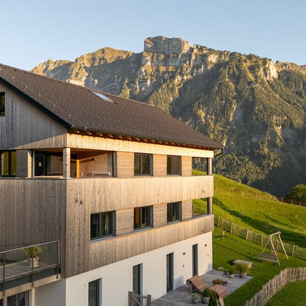 Außenansicht des Bauernhofs mit Holzverkleidung, Balkonen und Blick auf die Berge.