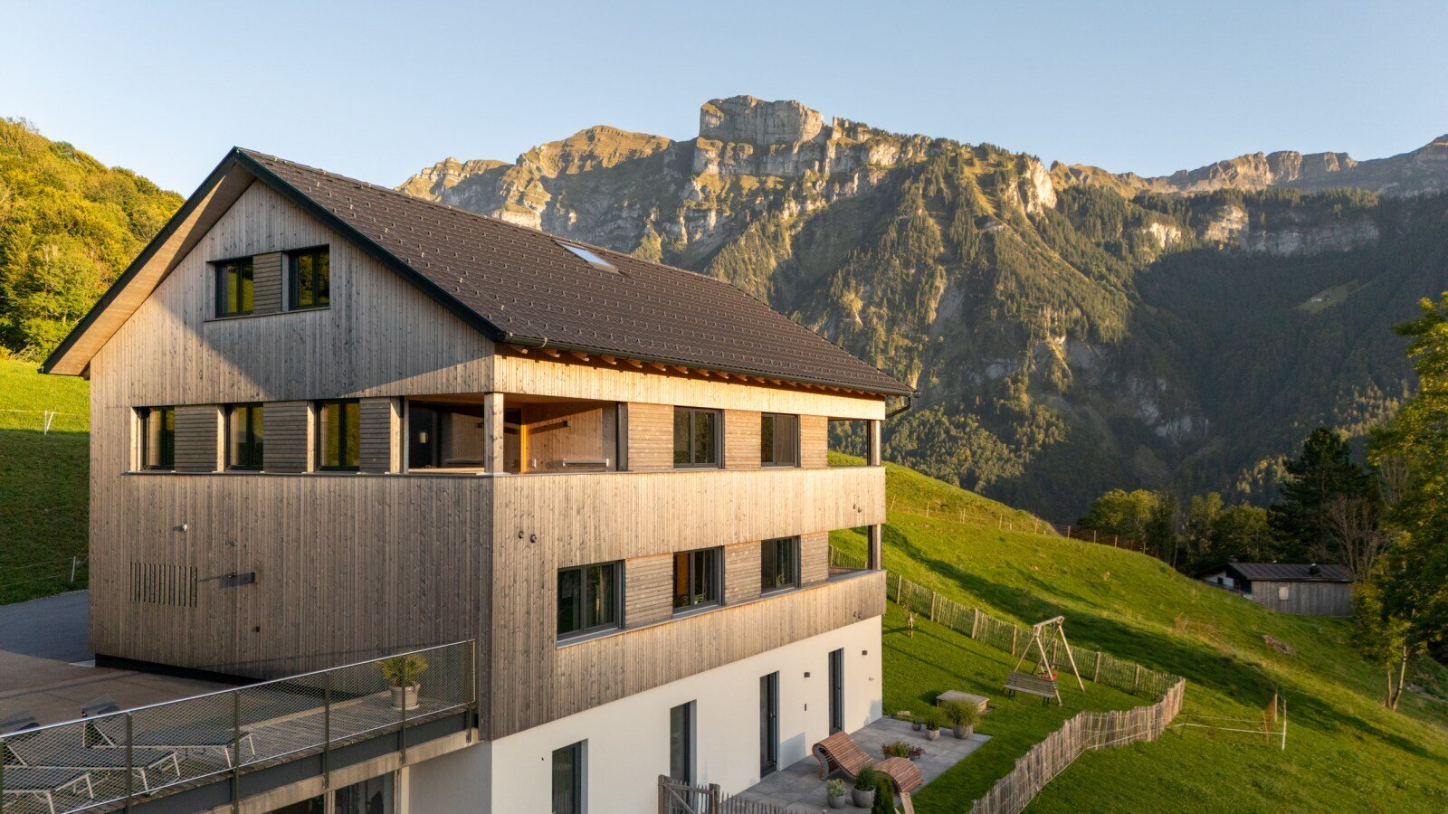 Außenansicht des Bauernhofs mit Holzverkleidung, Balkonen und Blick auf die Berge.